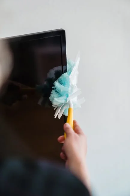 Anonymous person in yellow rubber gloves using simple sponge for cleaning mirror in bathroom